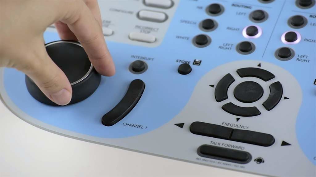 Close up of a hearing testing machine with a person's hand turning the buttons.